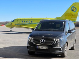 A yellow ambulance plane is parked behind a limousine from Access Oslo, at Gardermoen Airport